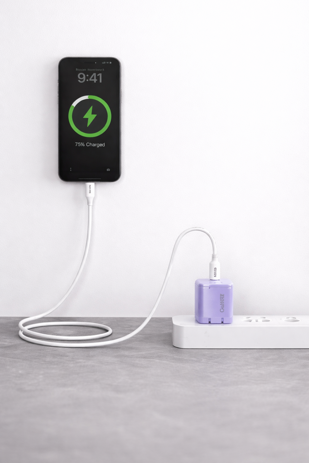 Smartphone charging on a white surface with a power adapter.